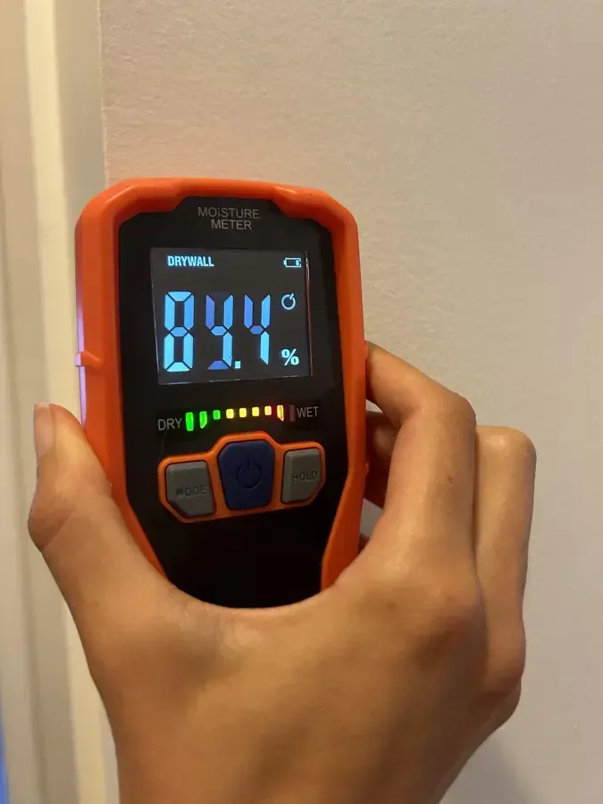 Pinless moisture meter checking a wall for hidden water during drying