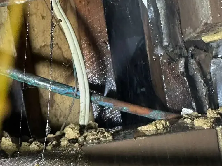 Water dripping from a leaking supply pipe inside an opened wall cavity