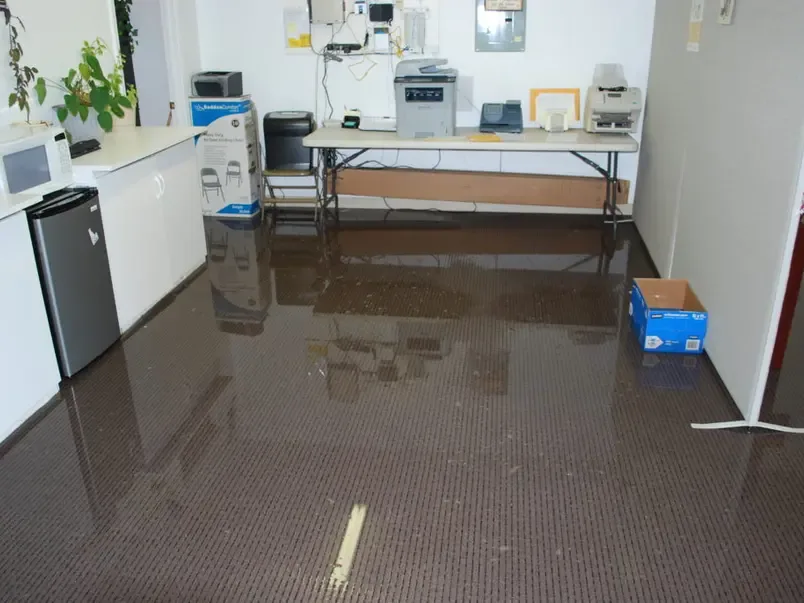 Standing water across the floor of an office with a copier and folding table